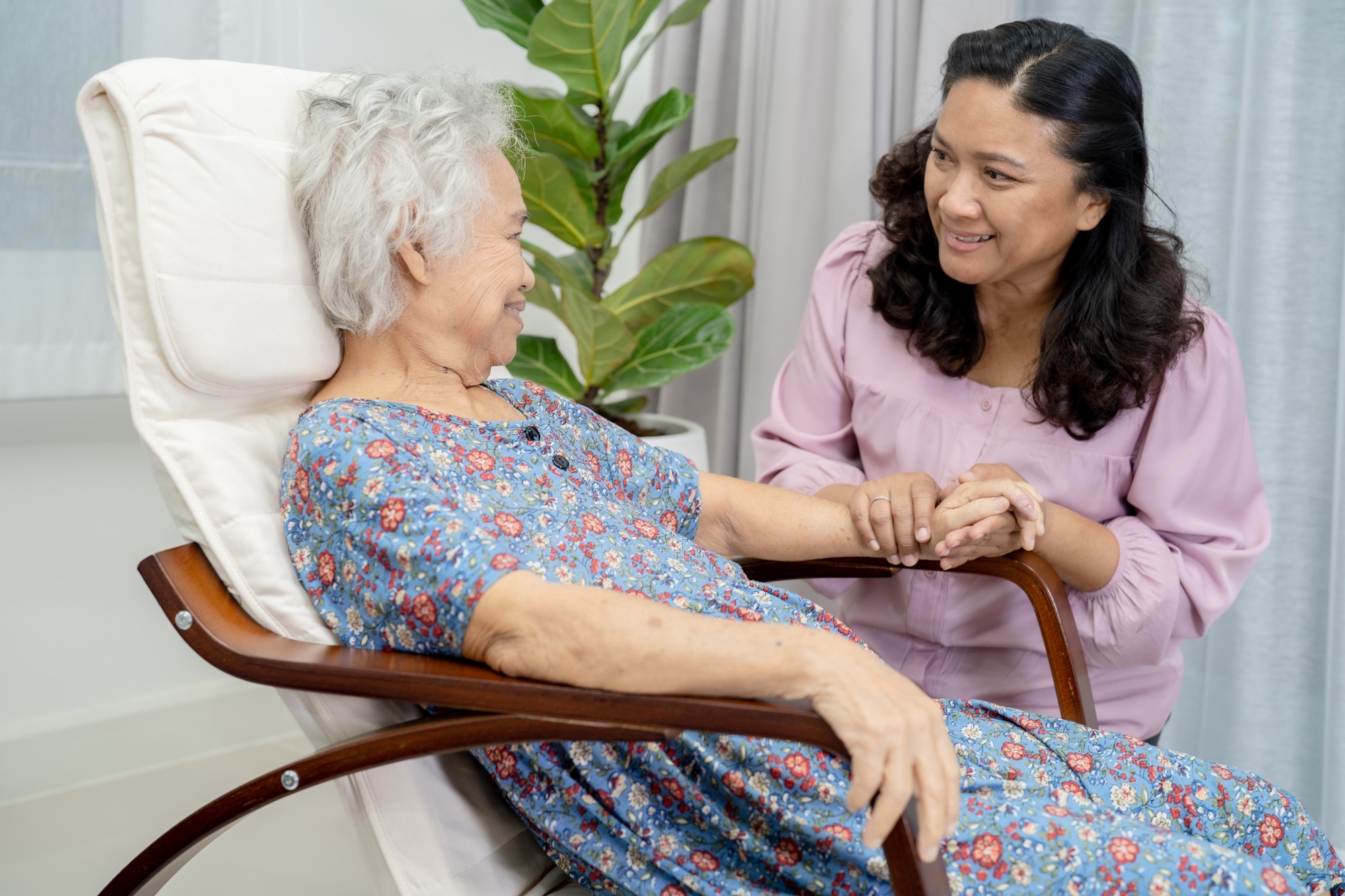Caregiver help and support Asian senior woman with love and care in home.