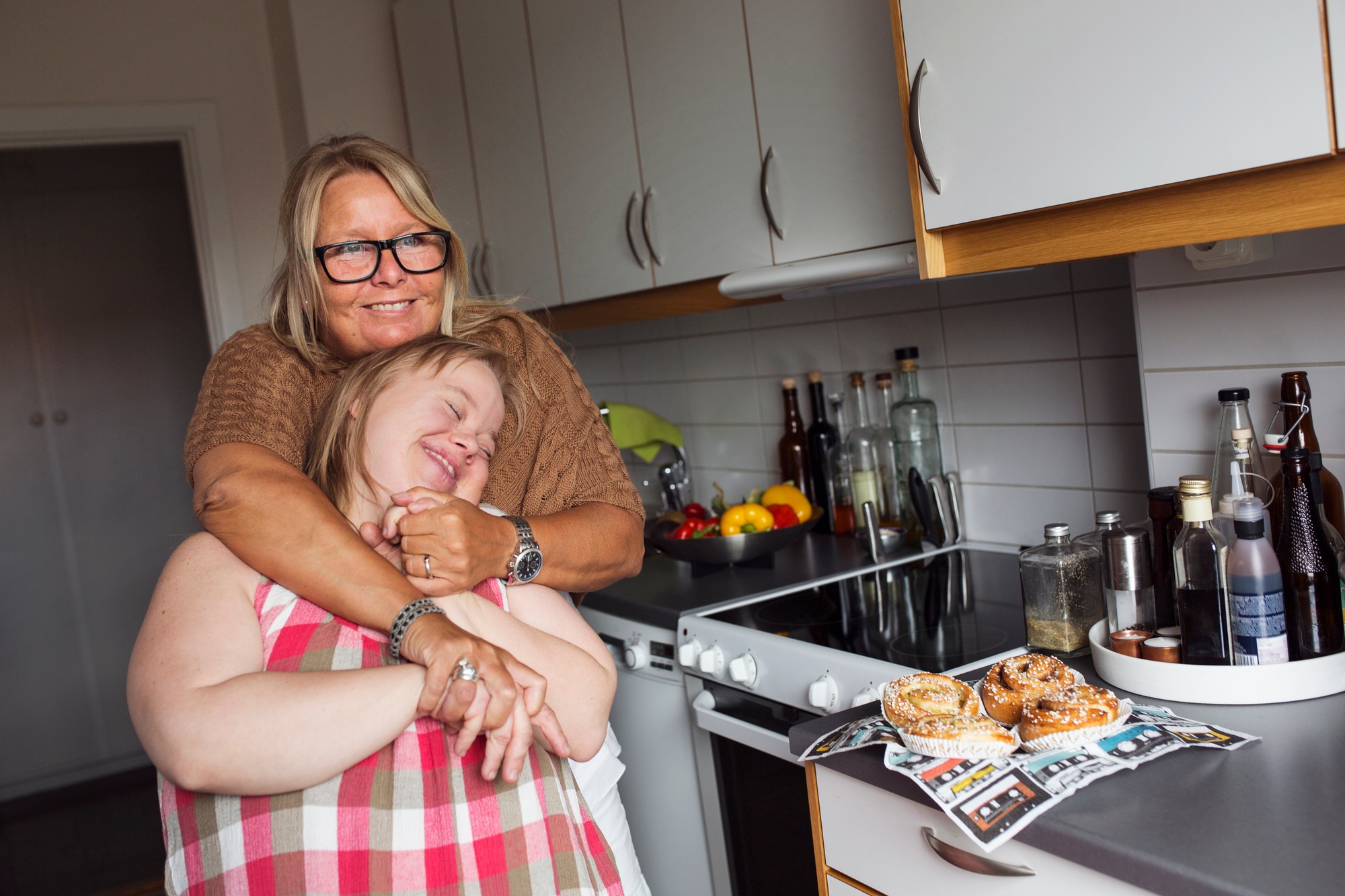 Mother hugging daughter with down syndrome in kitchen