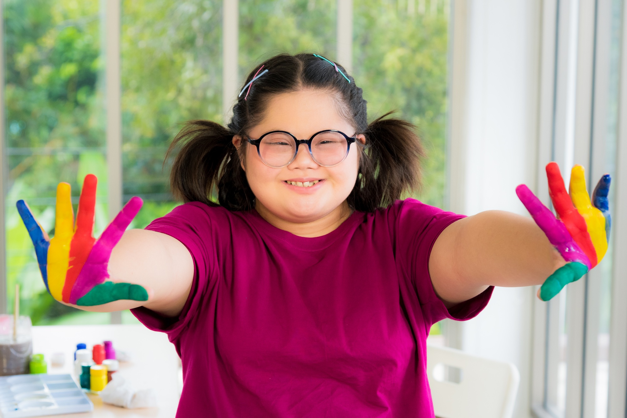 Autism disabled child kid complex genetic disorders down syndrome girl with colorful painted hands.